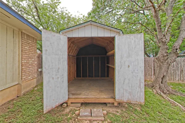 a backyard of a house with lots of plants and a tree