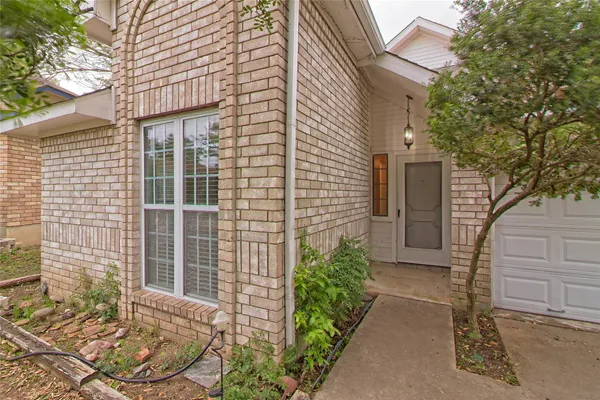 a view of a brick house with a large window and wooden fence