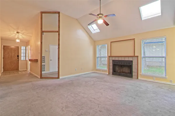 an empty room with fan fireplace and windows