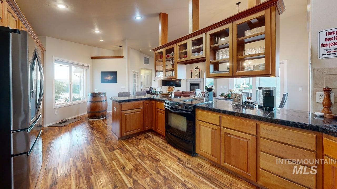 1724 Ridgeview Drive Clarkston, WA 99403 - Photo 7 of 48 Kitchen featuring glass insert cabinets, stainless steel fridge with ice dispenser, black range, light wood-style floors, and brown cabinets