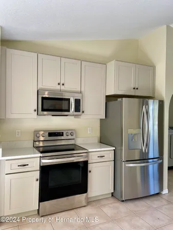 a kitchen with stainless steel appliances a refrigerator stove and white cabinets