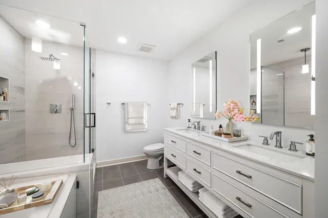 a bathroom with a double vanity sink toilet mirror and shower