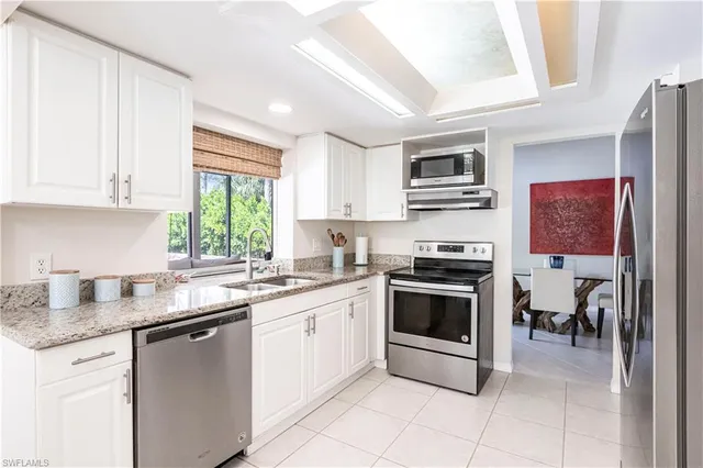 a kitchen with granite countertop a refrigerator and a stove top oven