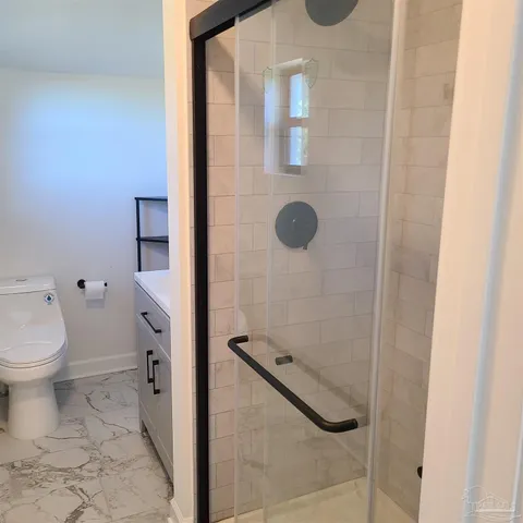 a bathroom with a granite countertop toilet and a shower