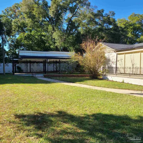 a view of swimming pool with lawn chairs and large trees