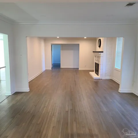 a view of empty room with a fireplace and wooden floor