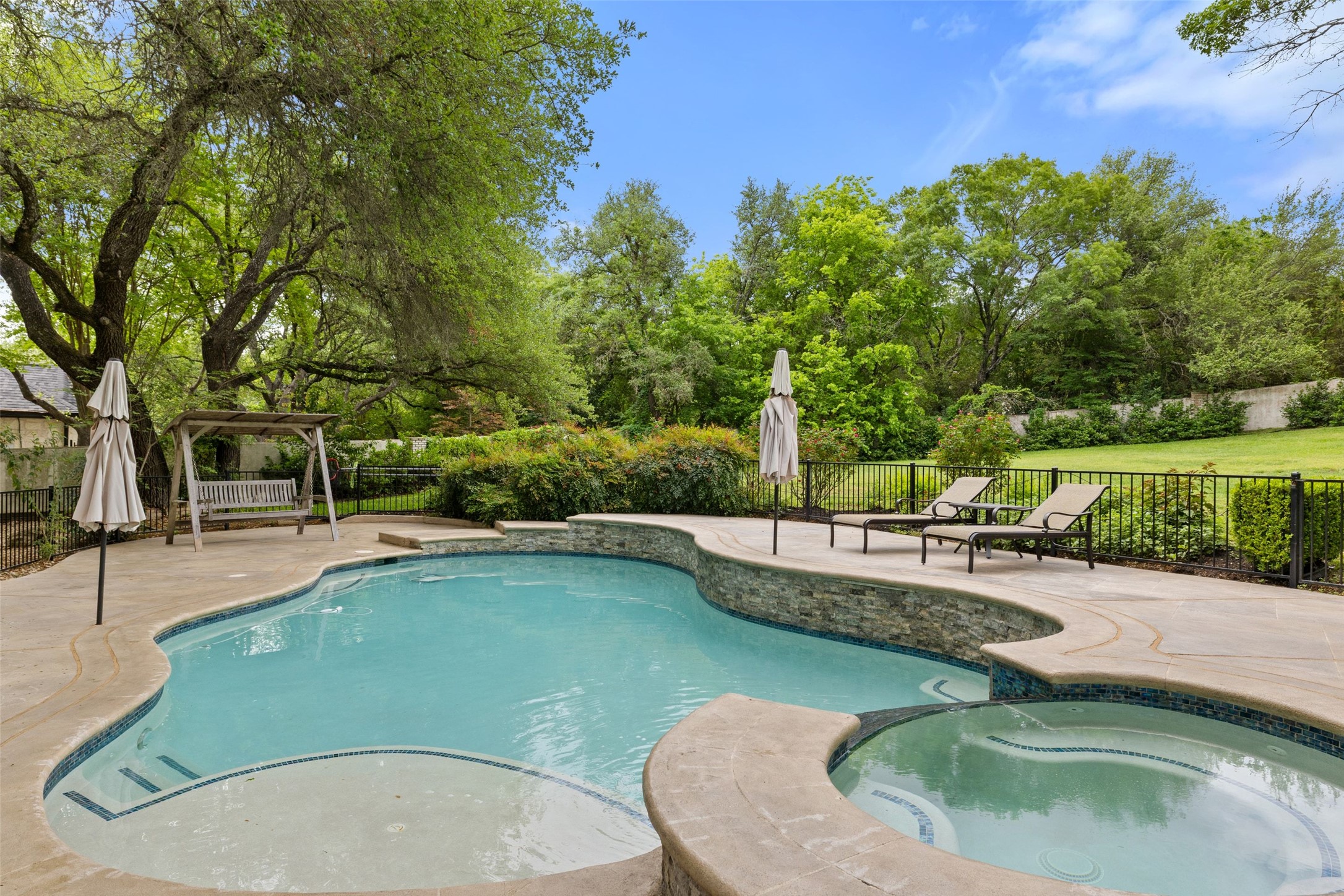 7609 Sandia Loop Austin, TX 78735 - Photo 30 of 40 Freeform swimming pool featuring a built-in spa, stone-finish accents, and integrated steps