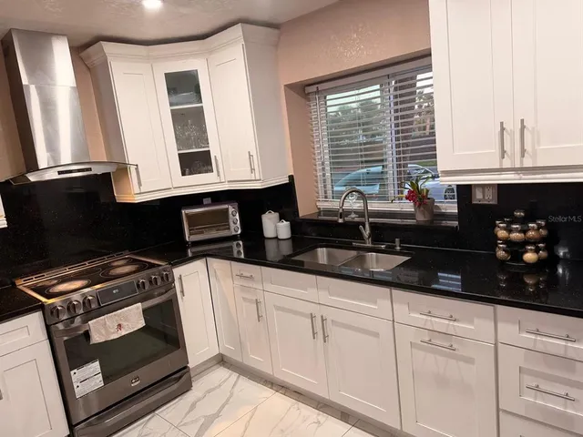 a kitchen with granite countertop a sink a stove and cabinets