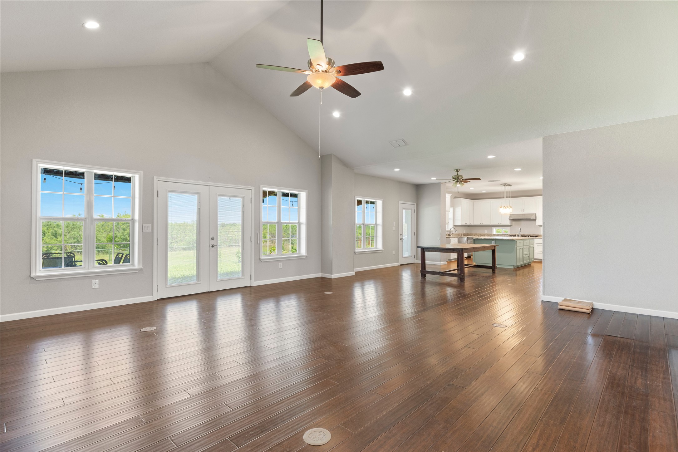 1293 Pioneer Road Seguin, TX 78155 - Photo 7 of 40 Hardwood floors and a soaring vaulted ceiling define this luminous, open-concept living space with a distant kitchen.