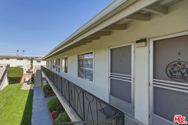 a view of empty room with wooden floor and kitchen