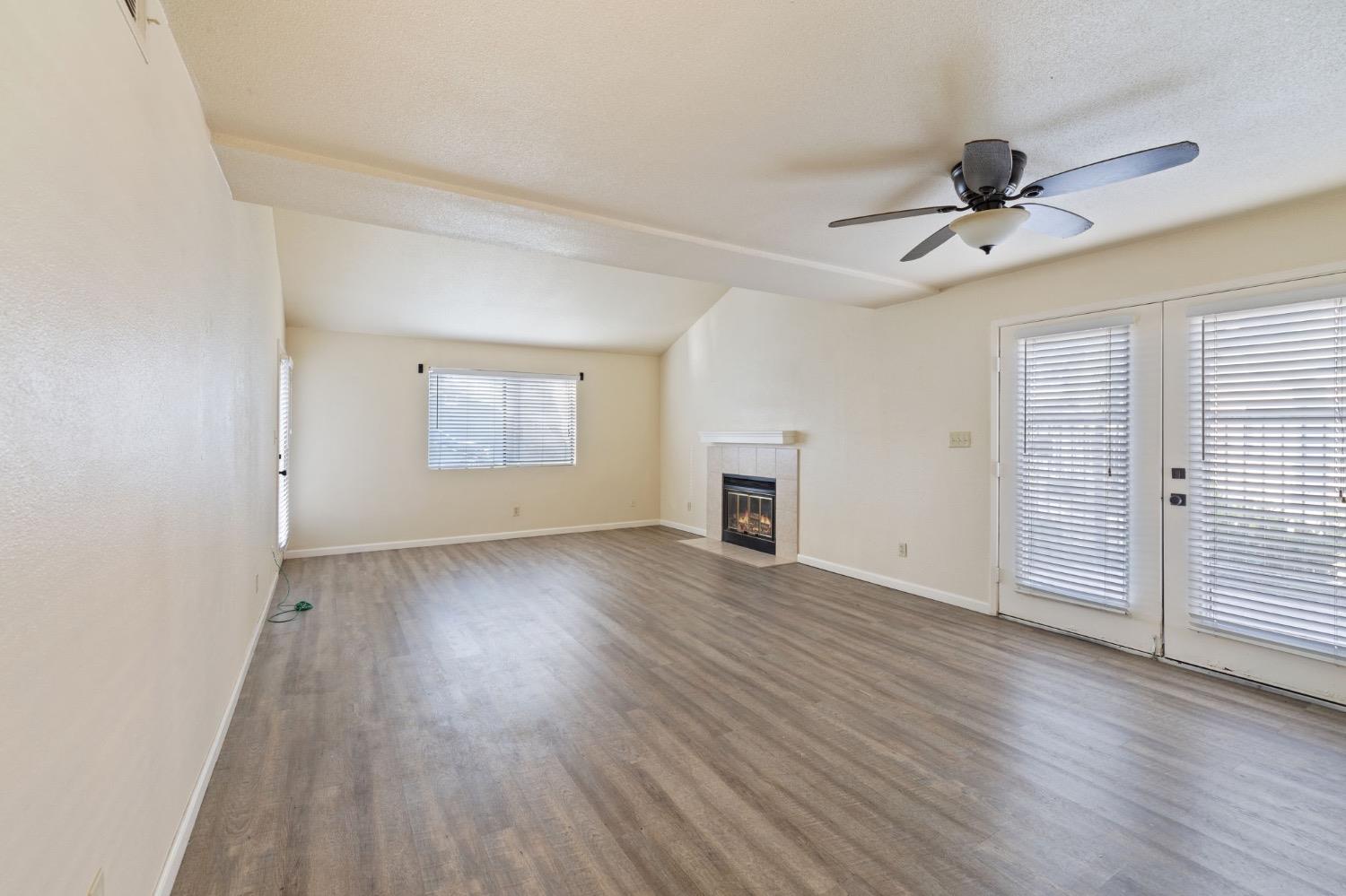 7675 North First Street, Unit 136 Fresno, CA 93720 - Photo 3 of 42 an empty room with wooden floor ceiling fan and windows