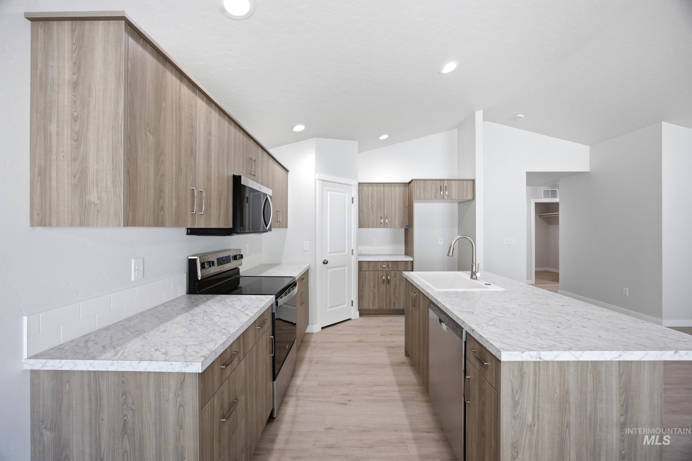 13298 Bank Street Caldwell, ID 83607 - Photo 5 of 23 Kitchen featuring wood-finish cabinetry, light-toned countertops, stainless steel appliances, a center island with sink, and recessed lighting