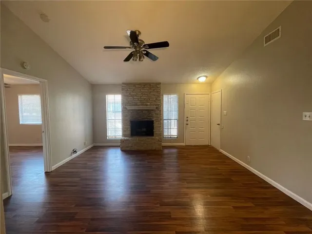 a view of an empty room with wooden floor and a fireplace