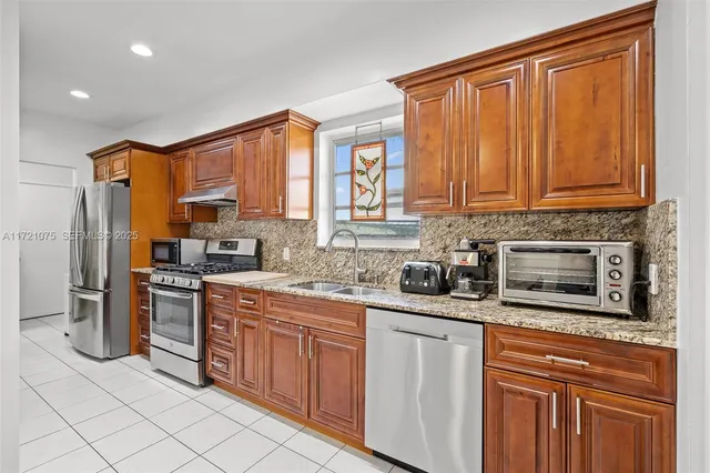 a kitchen with stainless steel appliances granite countertop a stove a sink dishwasher and a refrigerator