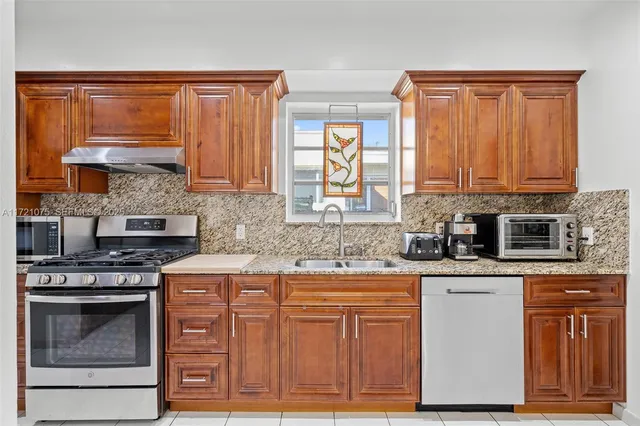 a kitchen with stainless steel appliances granite countertop a stove a sink and a microwave