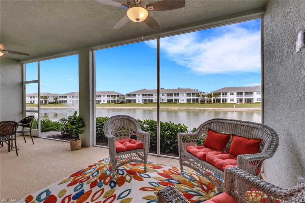 2647 Seychelles Circle, Unit 2202 Naples, FL 34112 - Photo 20 of 37 Sunroom / solarium featuring a textured ceiling, a residential view, expansive windows, a textured wall, and a water view
