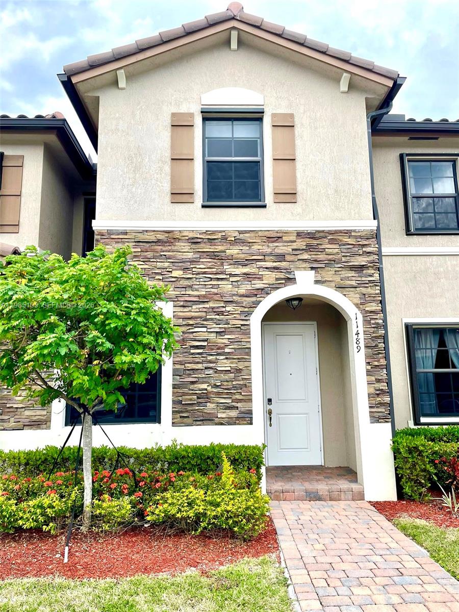 11489 Southwest 250th Street, Unit 11489 Homestead, FL 33032 - Photo 1 of 24 a front view of a house with garden