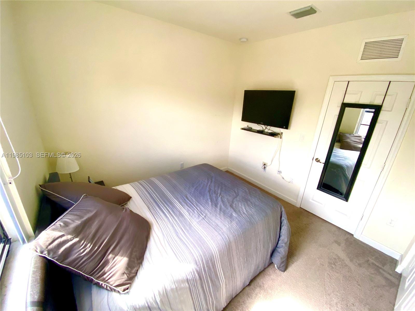 11489 Southwest 250th Street, Unit 11489 Homestead, FL 33032 - Photo 15 of 24 a bedroom with a bed and flat screen tv