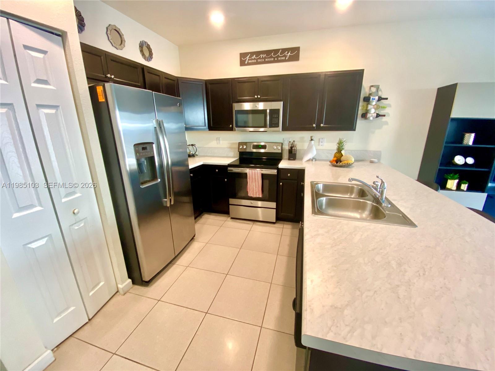 11489 Southwest 250th Street, Unit 11489 Homestead, FL 33032 - Photo 4 of 24 a kitchen with stainless steel appliances a refrigerator sink and microwave