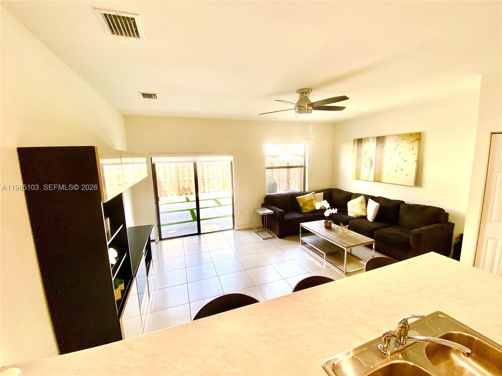 11489 Southwest 250th Street, Unit 11489 Homestead, FL 33032 - Photo 6 of 24 a living room with furniture and a flat screen tv