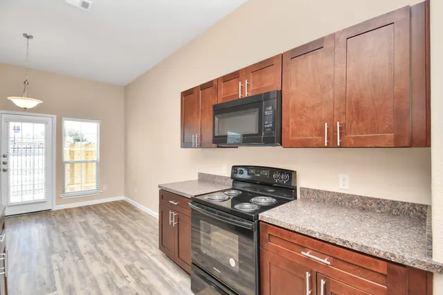 a kitchen with stainless steel appliances granite countertop a stove a sink and a microwave