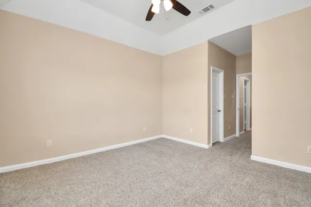 an empty room with a ceiling fan and carpet