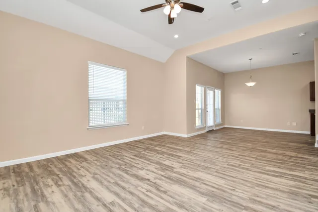 a view of an empty room with window and wooden floor