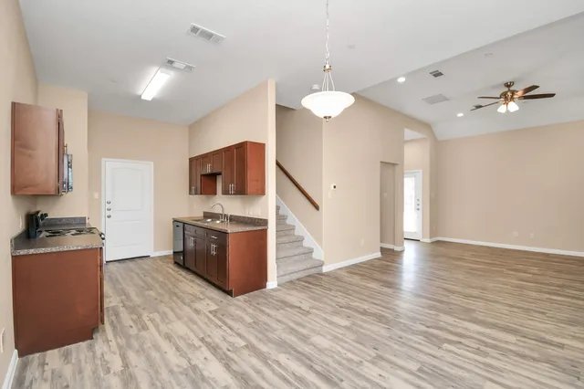 a large kitchen with stainless steel appliances granite countertop a stove and a wooden floors