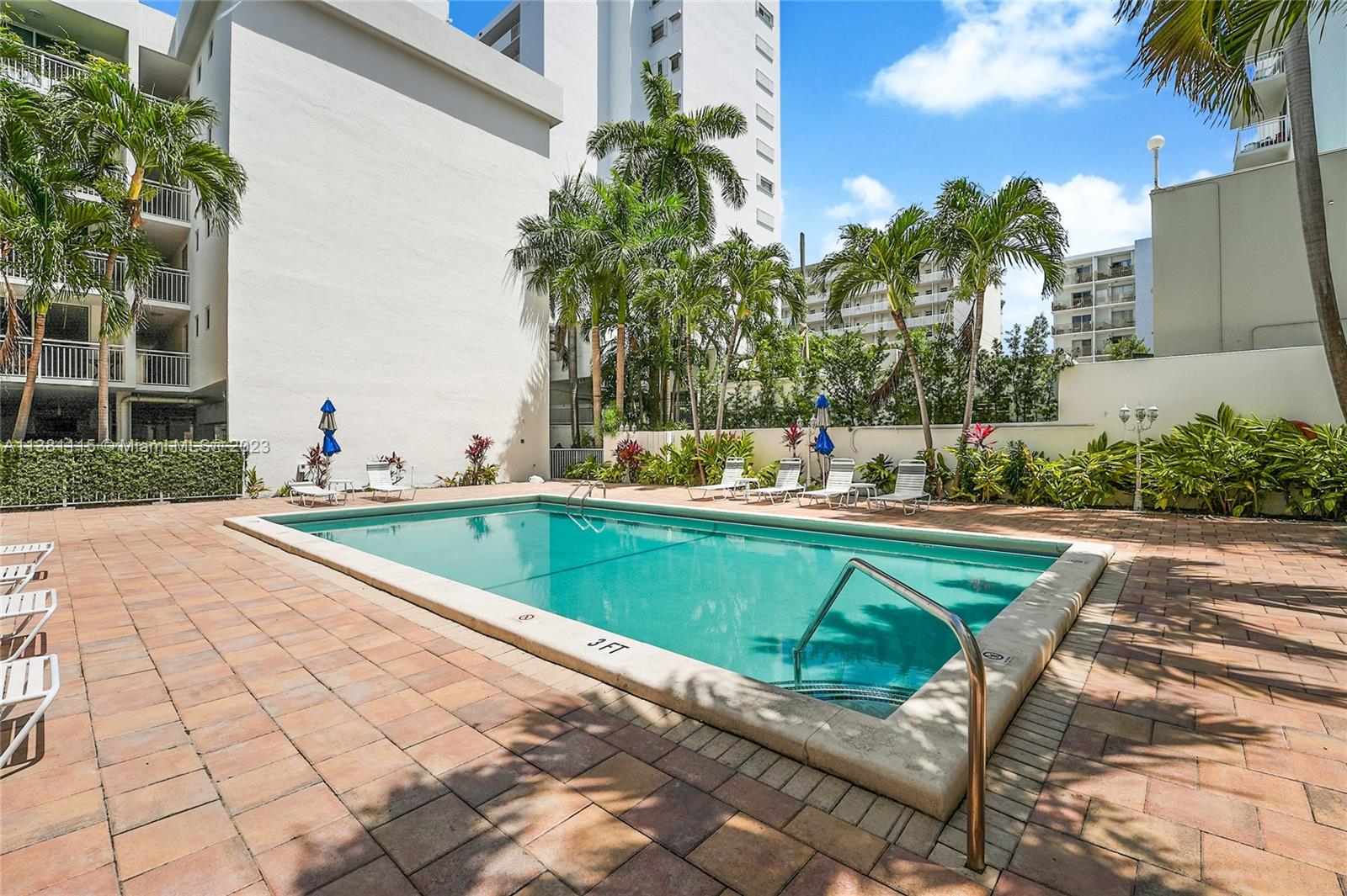 1665 Bay Road, Unit 417 Miami Beach, FL 33139 - Photo 15 of 15 a view of swimming pool that has lawn chairs with plants and palm trees