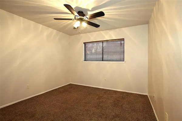 an empty room with a ceiling fan and a window