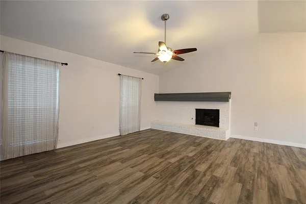 a view of empty room with wooden floor and fireplace