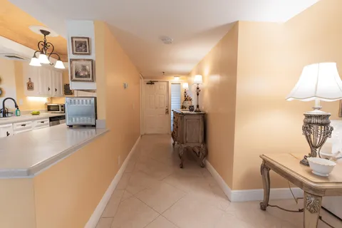 a hall way with furniture a rug and a lamp
