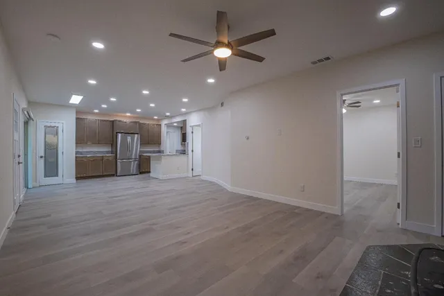 an empty room with wooden floor and a kitchen