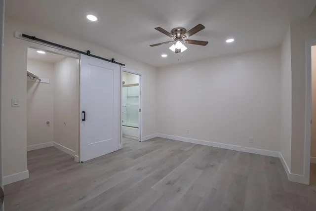 an empty room with wooden floor and ceiling fan