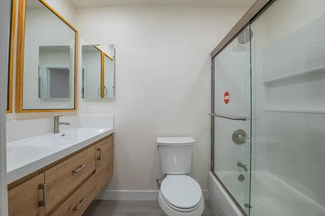 a bathroom with a double vanity sink toilet mirror and shower