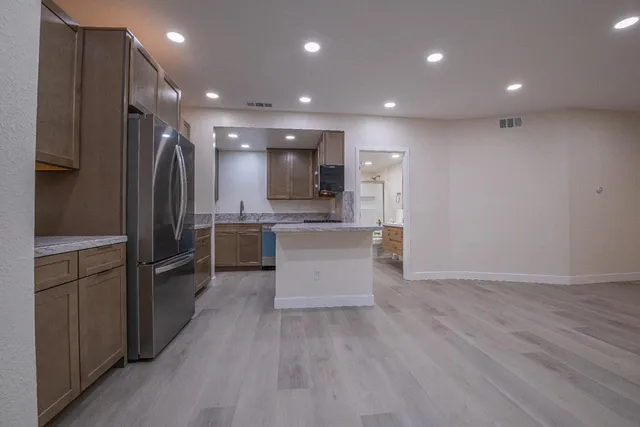 a kitchen with kitchen island granite countertop cabinets and refrigerator