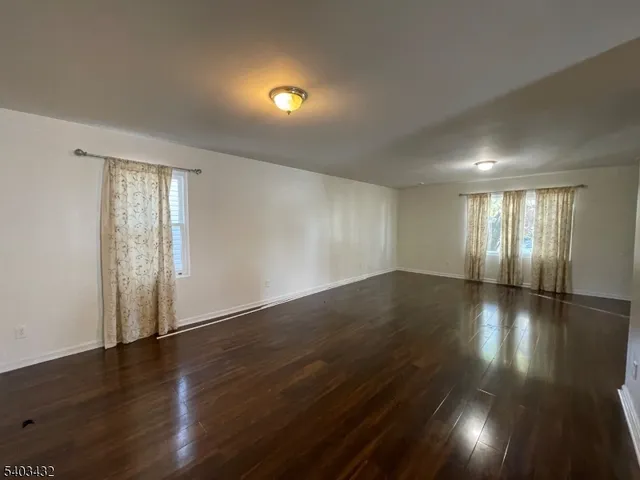 a view of an empty room with wooden floor and windows