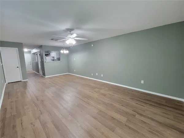 a view of a big room with wooden floor and a ceiling fan