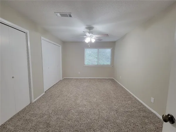 an empty room with a window and a ceiling fan