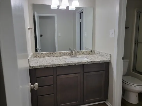 a bathroom with a granite countertop sink and a toilet