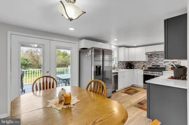 a kitchen with granite countertop a stove a sink a dining table and chairs