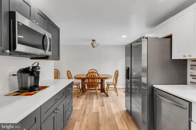 a kitchen with stainless steel appliances granite countertop a stove a refrigerator a sink dishwasher a dining table and chairs with wooden floor