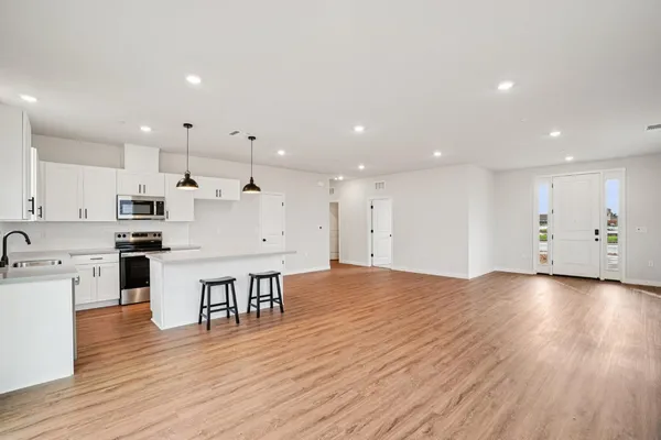 an open kitchen with white cabinets wooden floor and stainless steel appliances