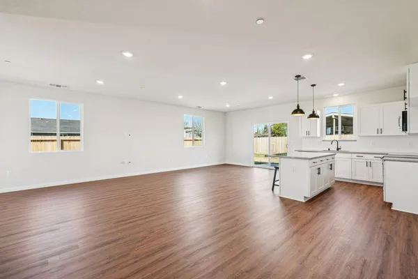 a large white kitchen with lots of counter space wooden floor and stainless steel appliances
