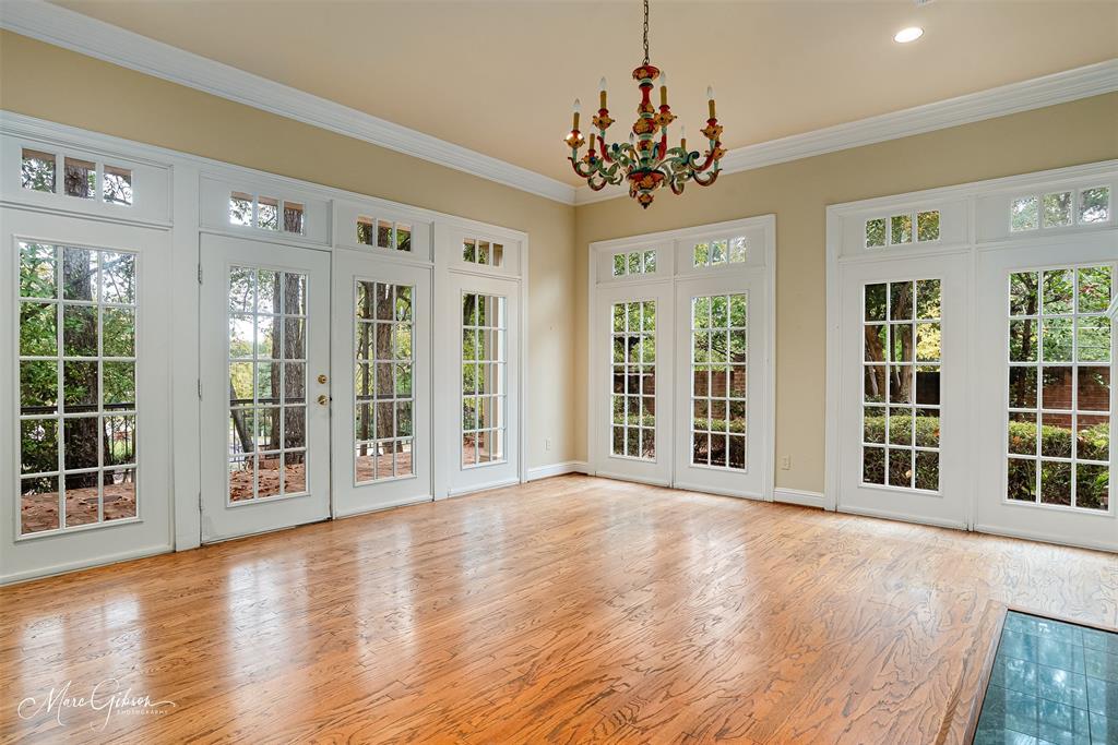 a view of an empty room with wooden floor and windows