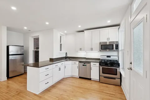 a large kitchen with stainless steel appliances granite countertop a stove and a refrigerator