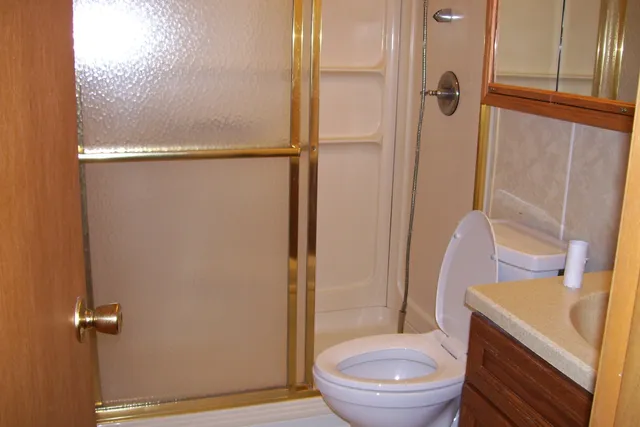 a bathroom with a granite countertop toilet and a shower