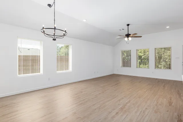 a view of an empty room with a window and wooden floor