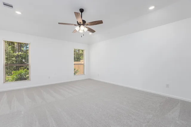 an empty room with windows and fan