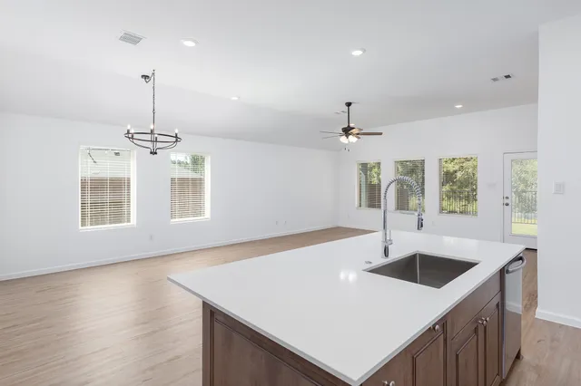 a kitchen with a sink chandelier and wooden floor